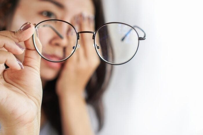 Woman hand holding eyeglasses having problem with blurry vision