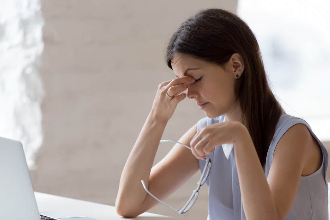 Young woman taking off glasses because of sore eyes.