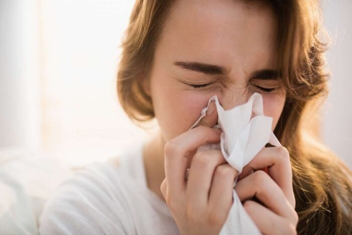 Woman blowing her nose because of hay fever
